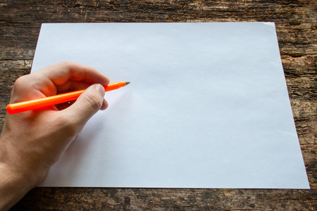 lefty writes with a ballpoint pen on a sheet of paper on wooden table International Lefthanders Dayの写真素材