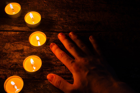 lighted candles and hand on a wooden backgroundの写真素材