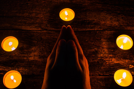 man reads a prayer surrounded by candlesの写真素材