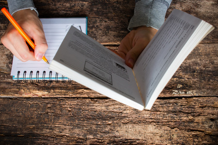 man reading a book and writes the acquired knowledgeの写真素材