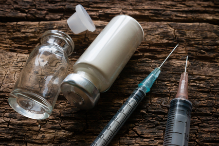 syringes and vials of medicine on a wooden backgroundの写真素材