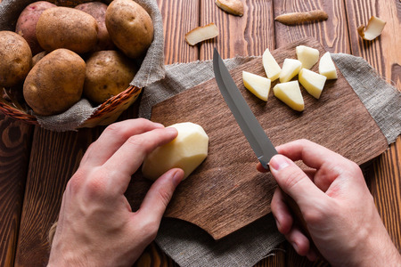 man cuts peeled potatoesの写真素材