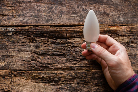 man holding a light bulb on a wooden background