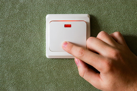 man turning off lights saves energyの写真素材