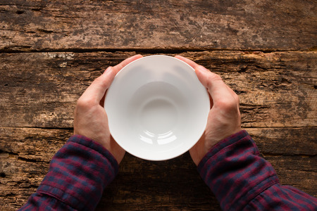 man holding a white empty cup on a wooden backgroundの写真素材