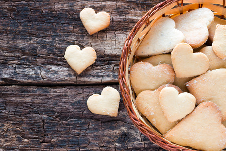 homemade cookies in the shape of a heart in a basket on a wooden tableの写真素材