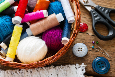 thread and yarn in a basket next to the buttons and scissorsの写真素材