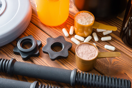 dumbbell with plastic stamp, and sports nutrition shaker on wooden backgroundの写真素材