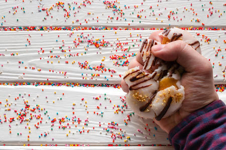 man squeezes a donut in his handの写真素材