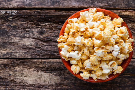 Popcorn in a bowl on a wooden background with space for textの写真素材
