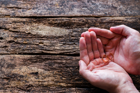man holding a gold ring on a wooden backgroundの写真素材