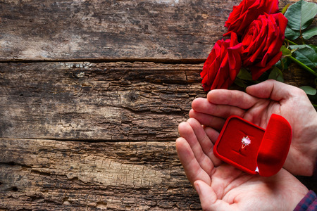 man giving a wedding ring and a bouquet of roses
