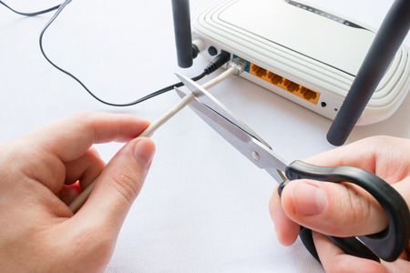 man cuts Internet cable connected to the routerの写真素材