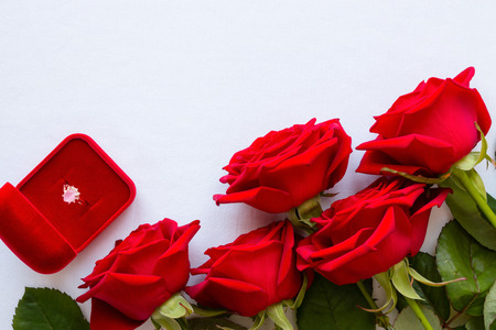 bouquet of red roses and a wedding ring on a white background with space for textの写真素材