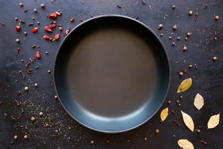 Empty frying pan and spices on a black backgroundの写真素材