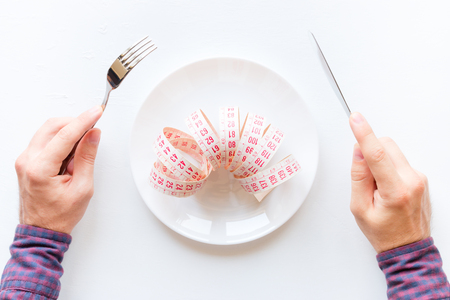 man eating a measuring tape in a plate on a white backgroundの写真素材