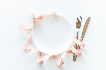 Empty dish with cutlery and measuring tape with space for textの写真素材