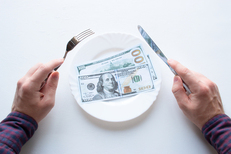 man with cutlery and money on a white plateの写真素材