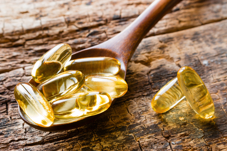 capsules of fish oil in a wooden spoon closeupの写真素材