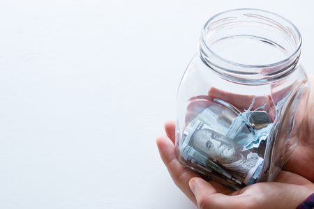 man holds a glass jar for donations with place for text on a white backgroundの写真素材