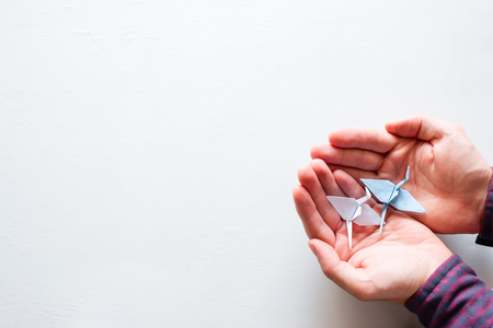 man holding a crane of origami on a white background with space for textの写真素材