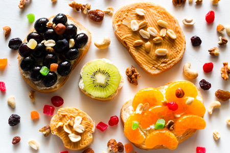 homemade cooked sandwiches with fruits and berries on a background of nuts and dried fruits close-upの写真素材