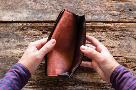 the man is looking at an empty purse. no money
