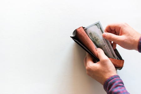 man takes out money from a purse on a white background with space for text