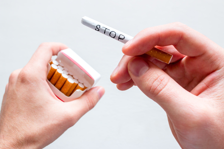 smoker holding a cigarette with the word stop. concept stop smoking on white backgroundの写真素材
