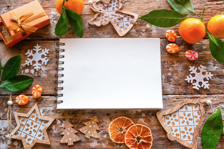 empty list of wishes and frame from Christmas decorations and tangerine on a wooden backgroundの写真素材