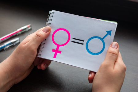 young woman shows a notepad with symbols of gender equality close-upの写真素材