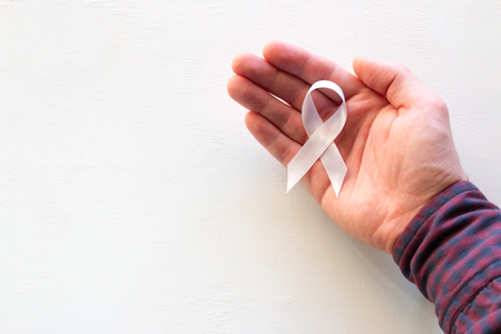 man hold white ribbon with place for text on white backgroundの写真素材