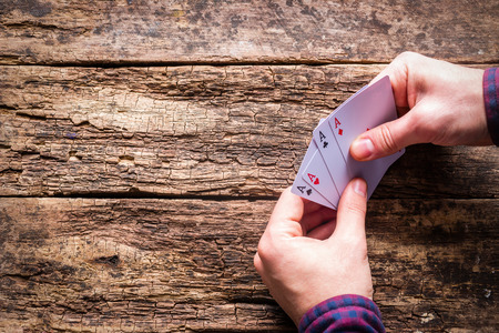 card player holds four aces on a wooden background with space for text.の写真素材