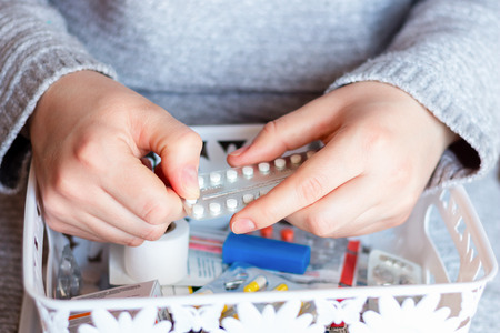 young woman pulls birth control pills from a first aid kitの写真素材