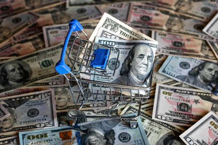 grocery cart with money on the background of dollar billsの写真素材