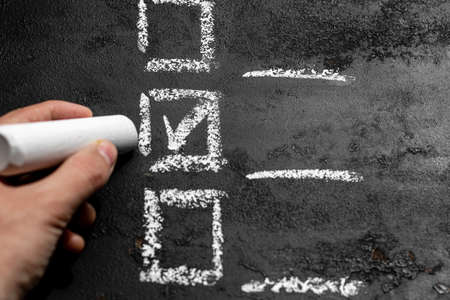 hand holds chalk and makes a choice. voting, checklist, option selection