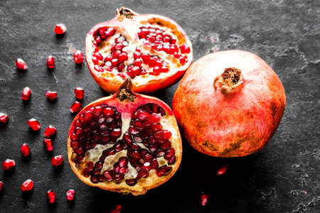 ripe pomegranate, slice and seeds on a black backgroundの写真素材
