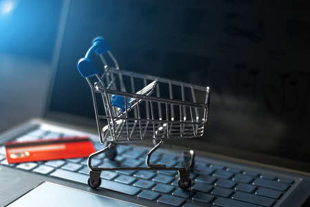 grocery cart on a computer keyboard and credit card on the background of an online store close-upの写真素材