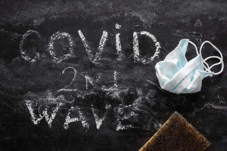 erased lettering second wave covid and used medical maskの写真素材