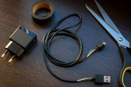 old mobile charger wire for smartphone with bare wires and electrical tape fix conceptの写真素材