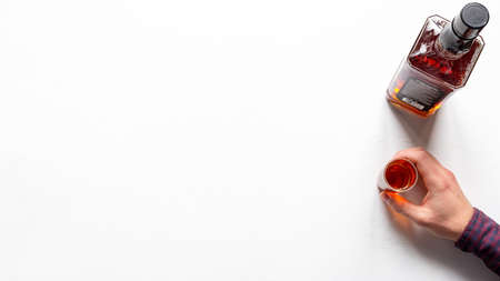 bottle of whiskey and hand holds a glass of alcohol alcoholism concept on white background with place for textの写真素材