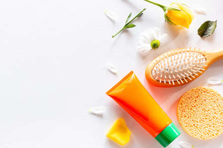 beauty products cosmetics, comb and flowers on white background with place for text