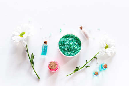 bath salt and home cosmetics cream oils and flowers on white background