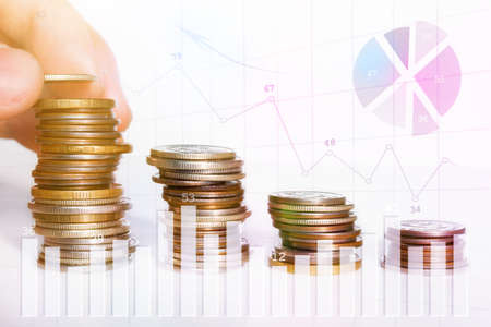 man puts a coin in a stack of coins, business growth concept close-upの写真素材