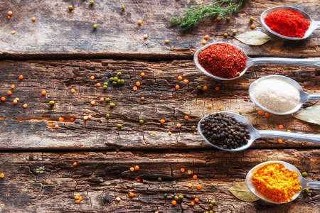 spices in tablespoons and herbs on a wooden background with place for textの写真素材