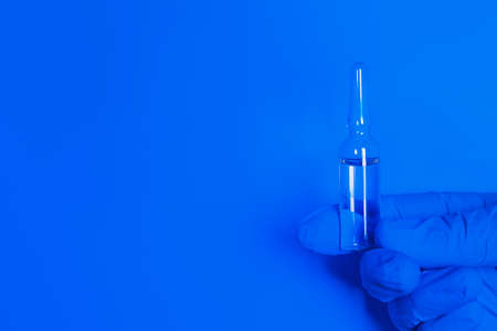 holding vaccine on blue background with place for textの写真素材