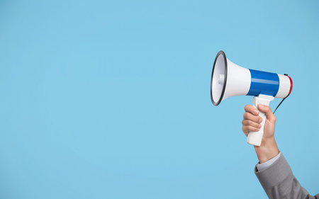 hand with megaphone on blue background with space for textの素材