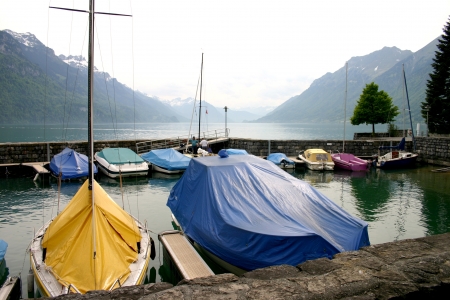 Boats moored on lake Brienz at Oberried near Interlaken with the swiss alps in the background の写真素材