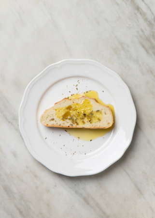 Slice of traditional bread with olive oil EVO, top view on marble top