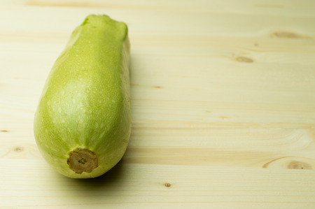 Zucchini on circle wooden plate on white isolated backgroundの写真素材